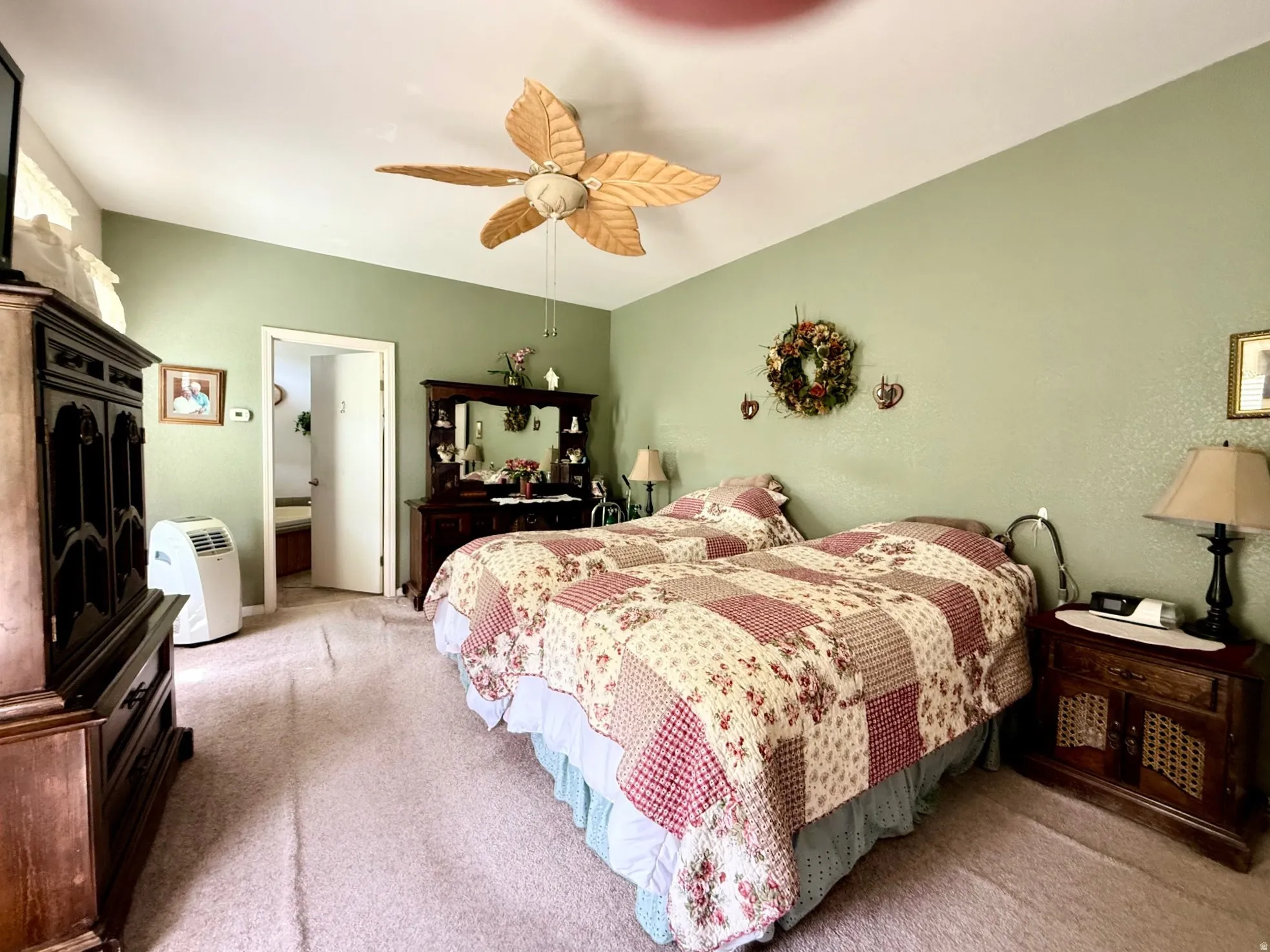 Bedroom with light carpet, connected bathroom, and ceiling fan
