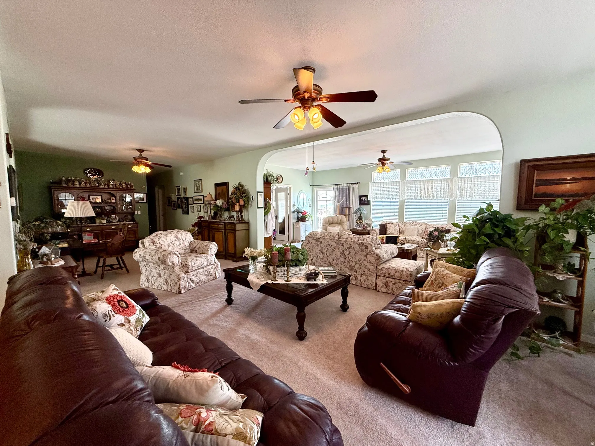 Carpeted living area featuring arched walkways and ceiling fan