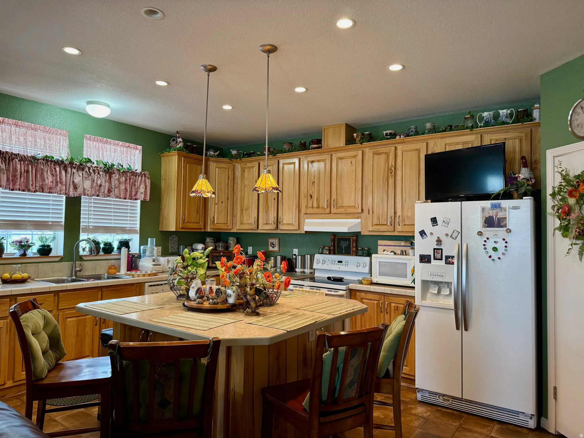Kitchen with white appliances, a kitchen breakfast bar, pendant lighting, a center island, and tile countertops