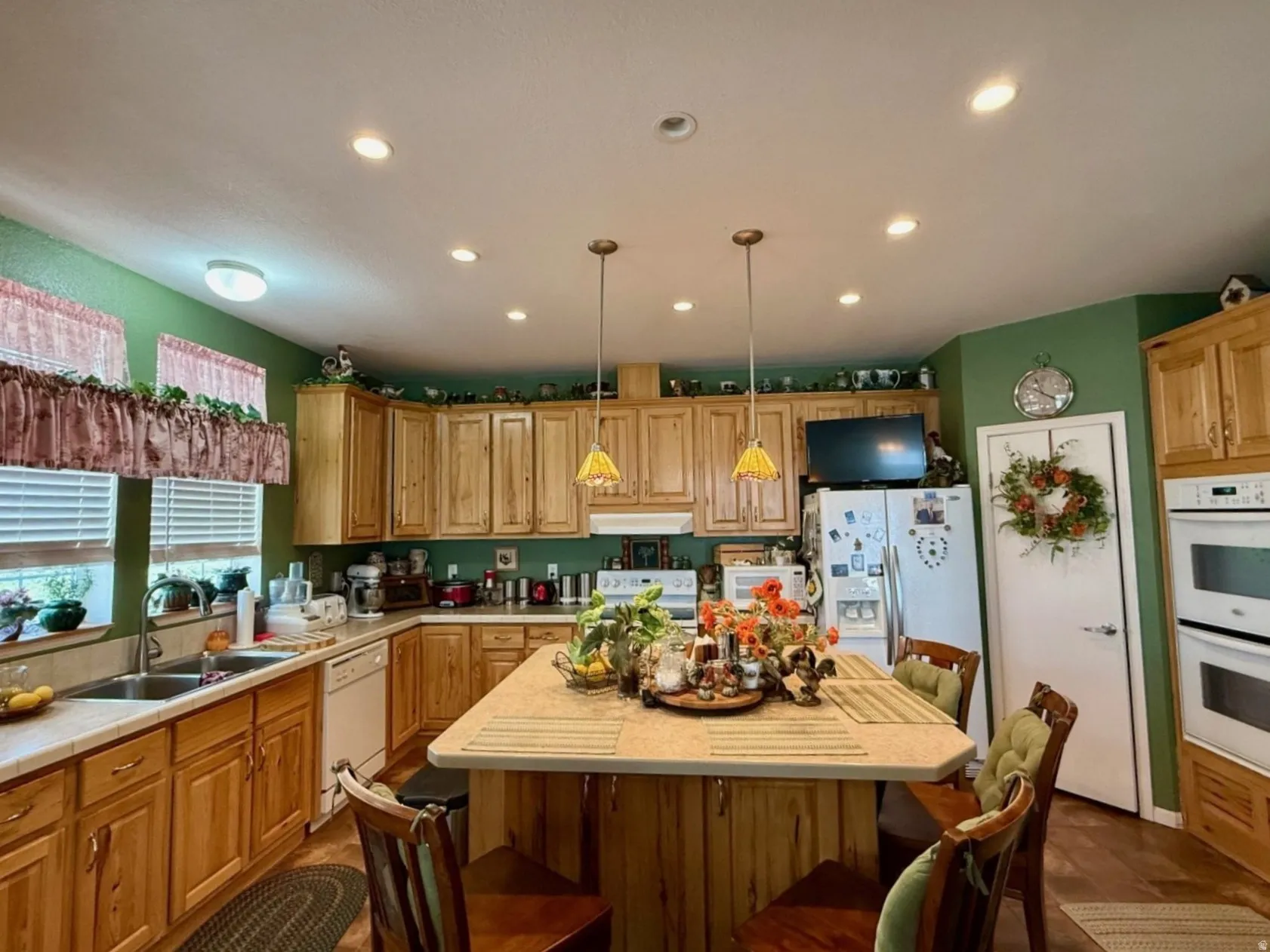 Kitchen featuring white appliances, a center island, pendant lighting, a kitchen breakfast bar, and wood finish cabinets