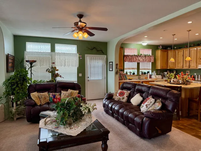 Living room featuring arched walkways, ceiling fan, recessed lighting, and light colored carpet