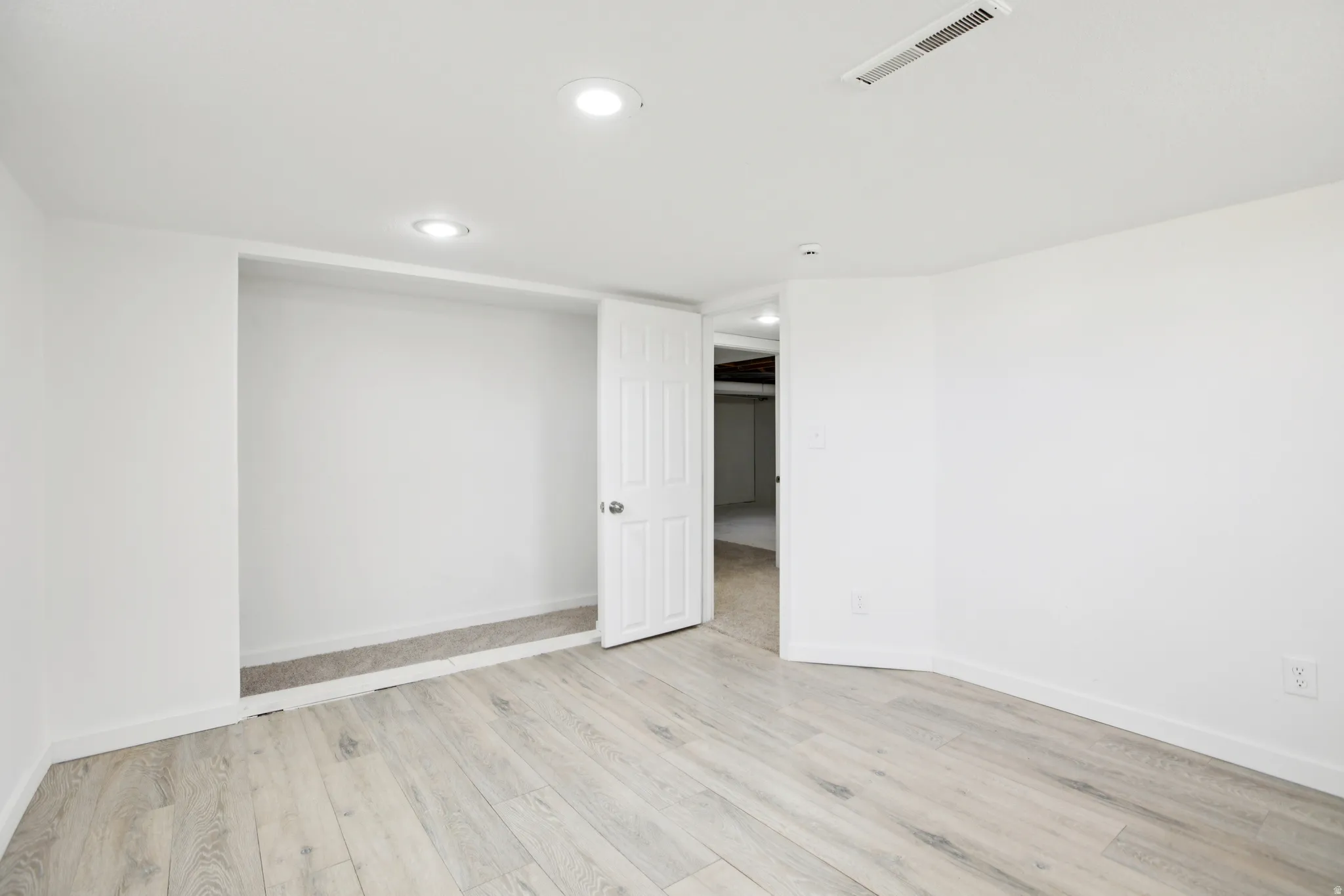 Empty room with light wood-style flooring and recessed lighting