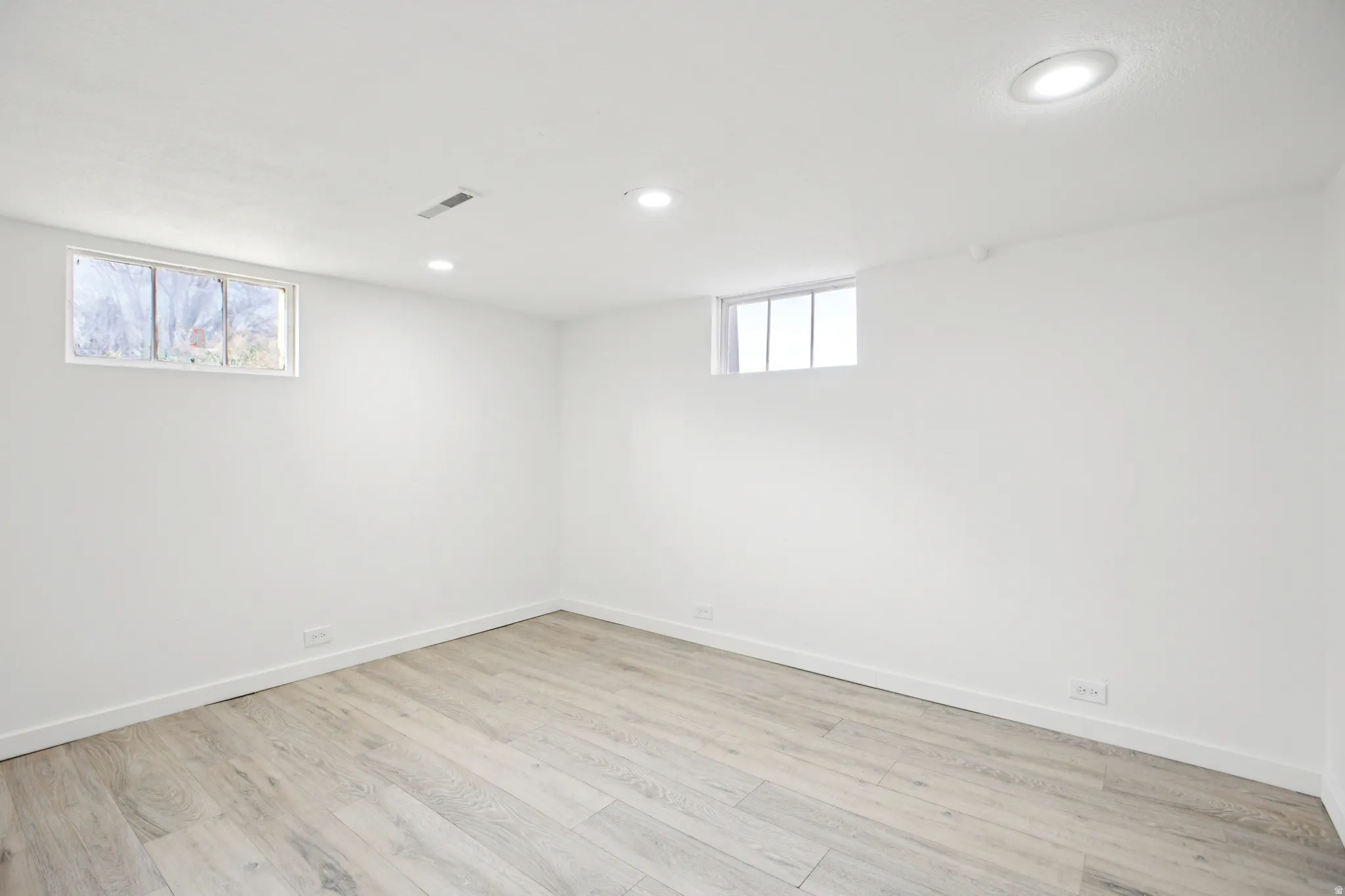 Basement with light wood-style floors and recessed lighting