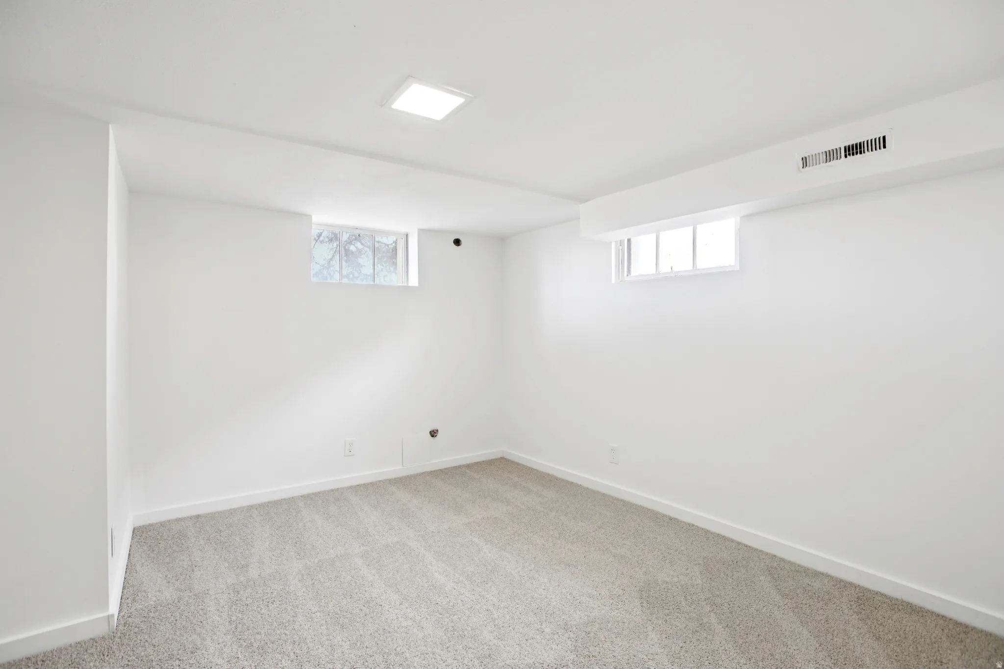 Basement with light carpet and plenty of natural light