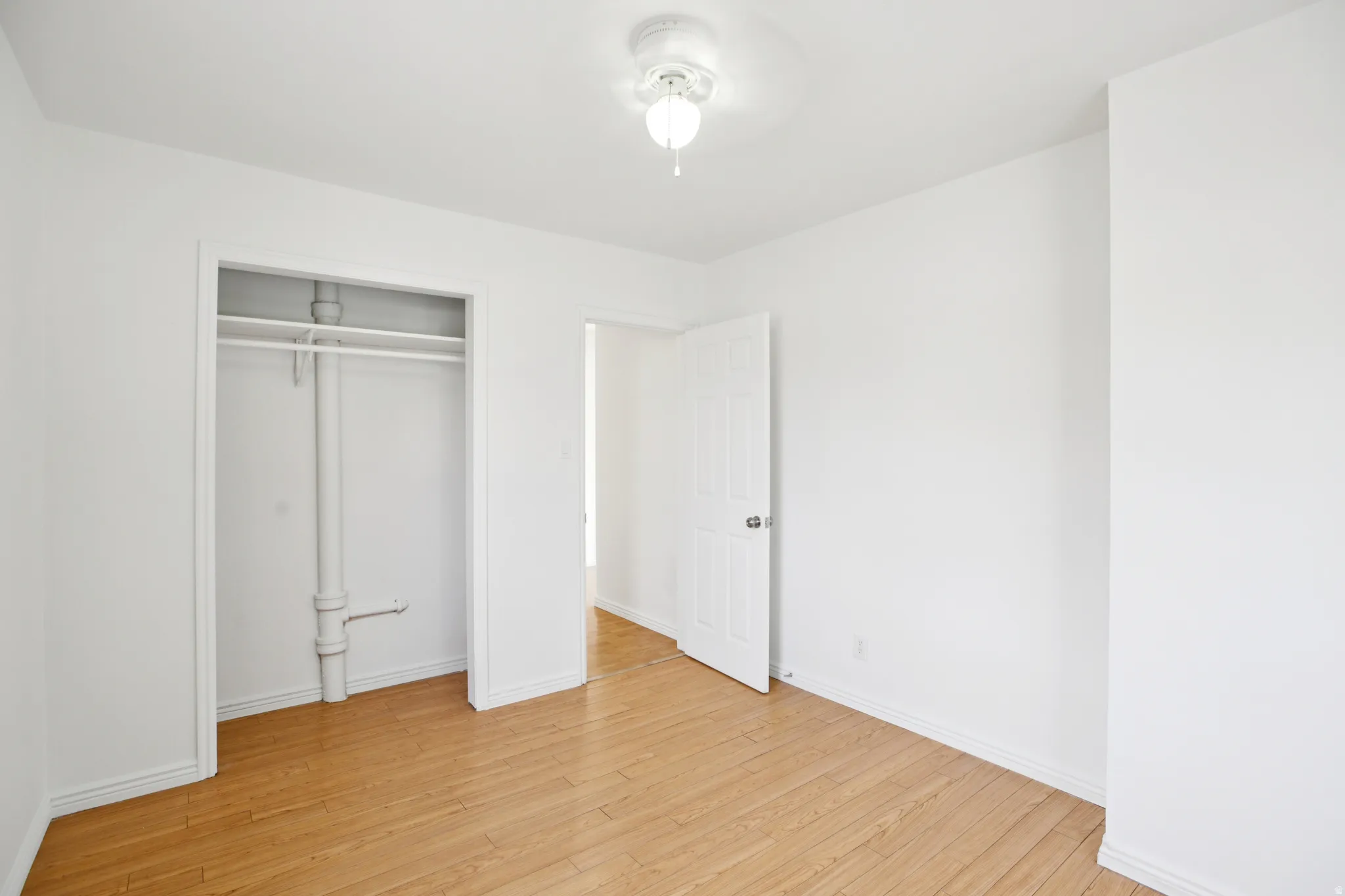 Unfurnished bedroom with light wood-style floors, a closet, and a ceiling fan