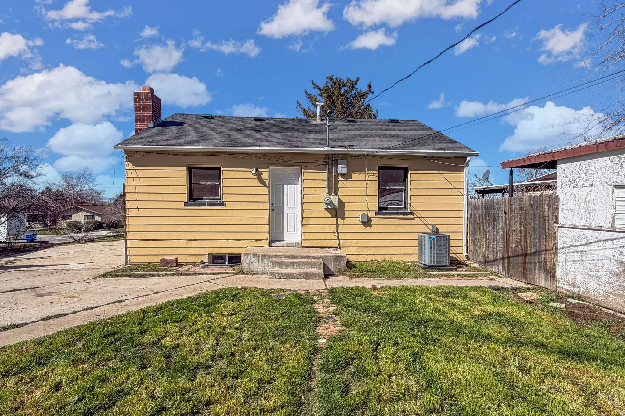 Rear view of house featuring a chimney and a shingled roof