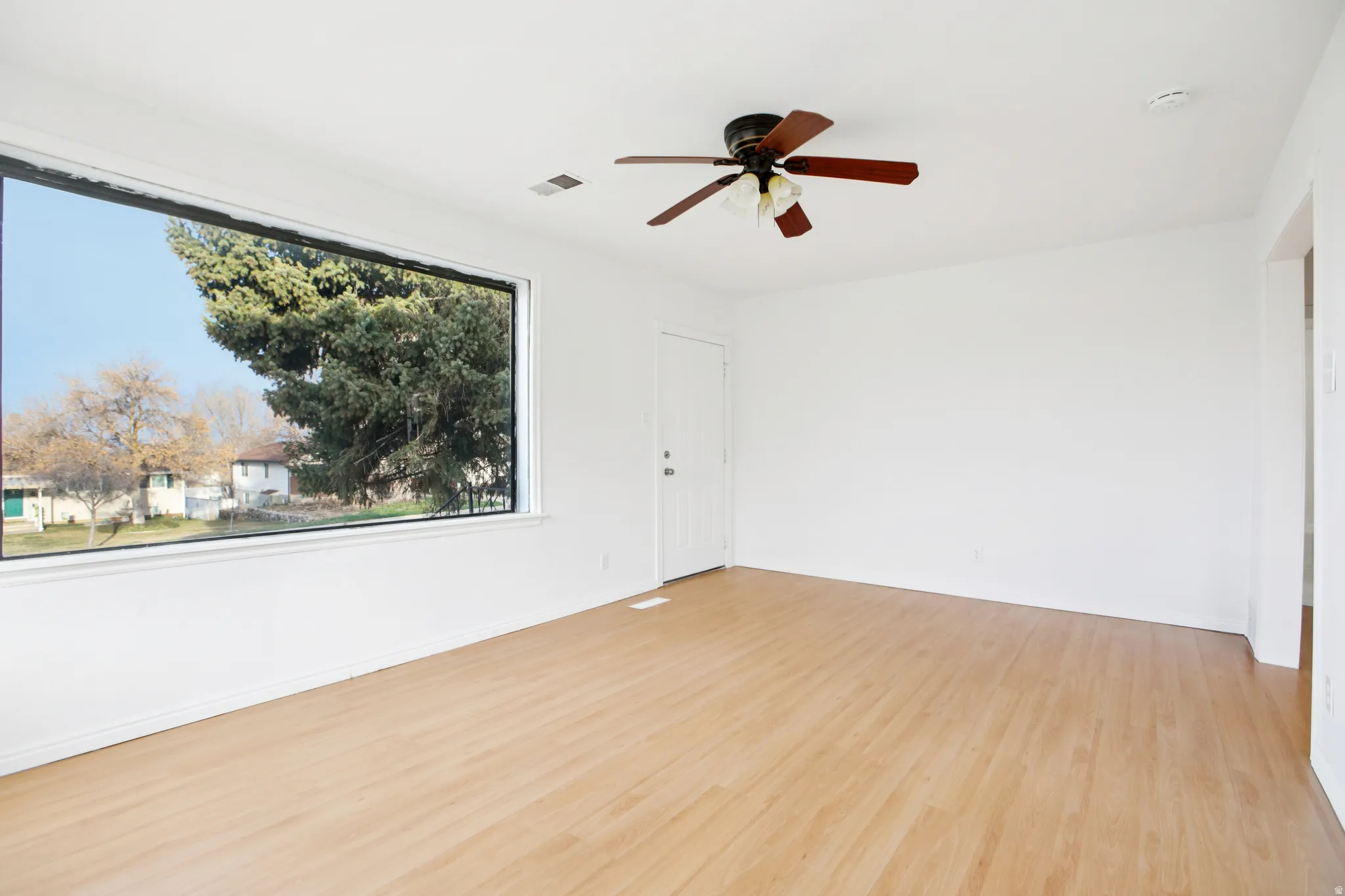 Unfurnished room with ceiling fan and light wood-style flooring