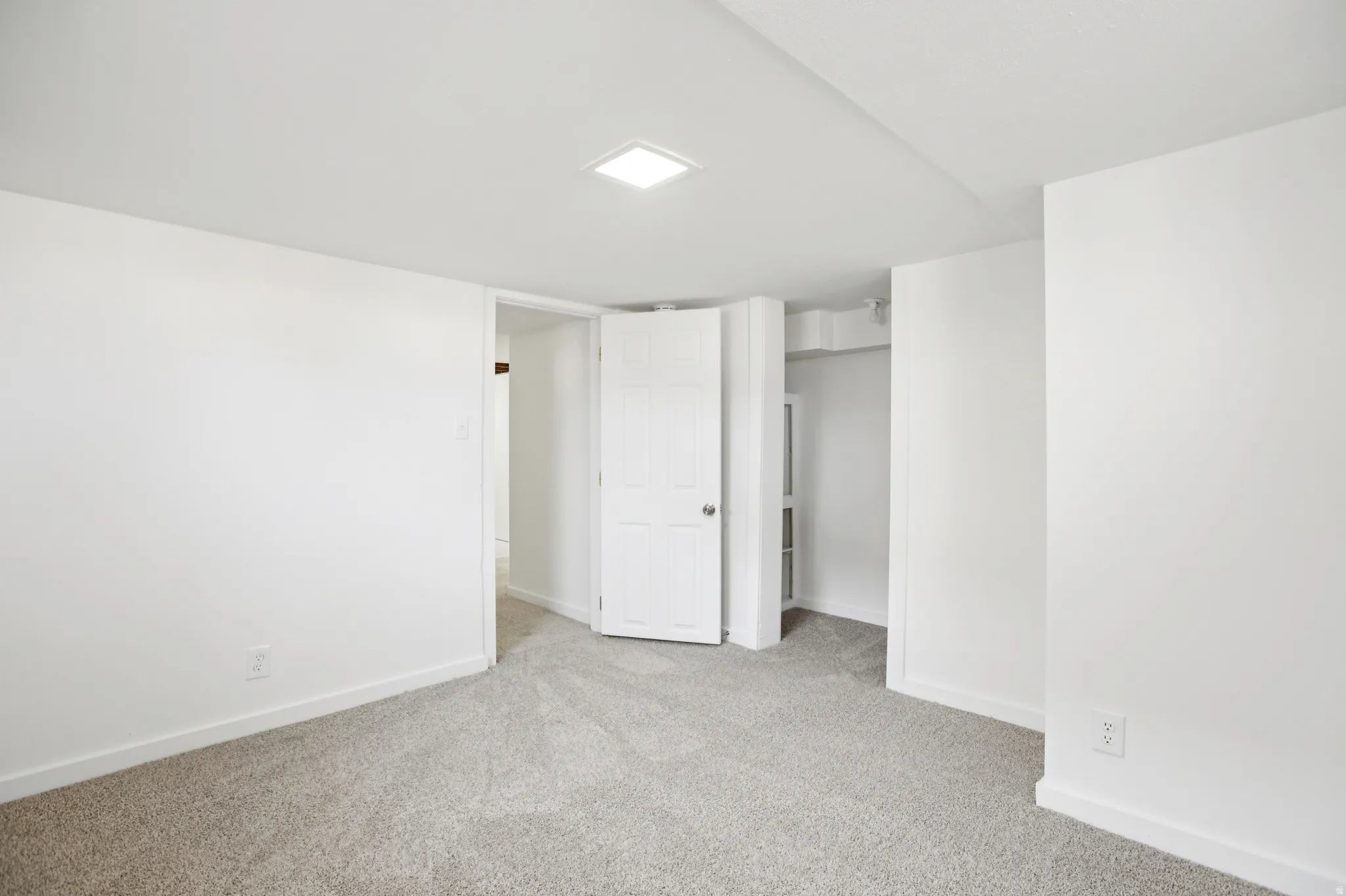 Unfurnished bedroom with light colored carpet and baseboards
