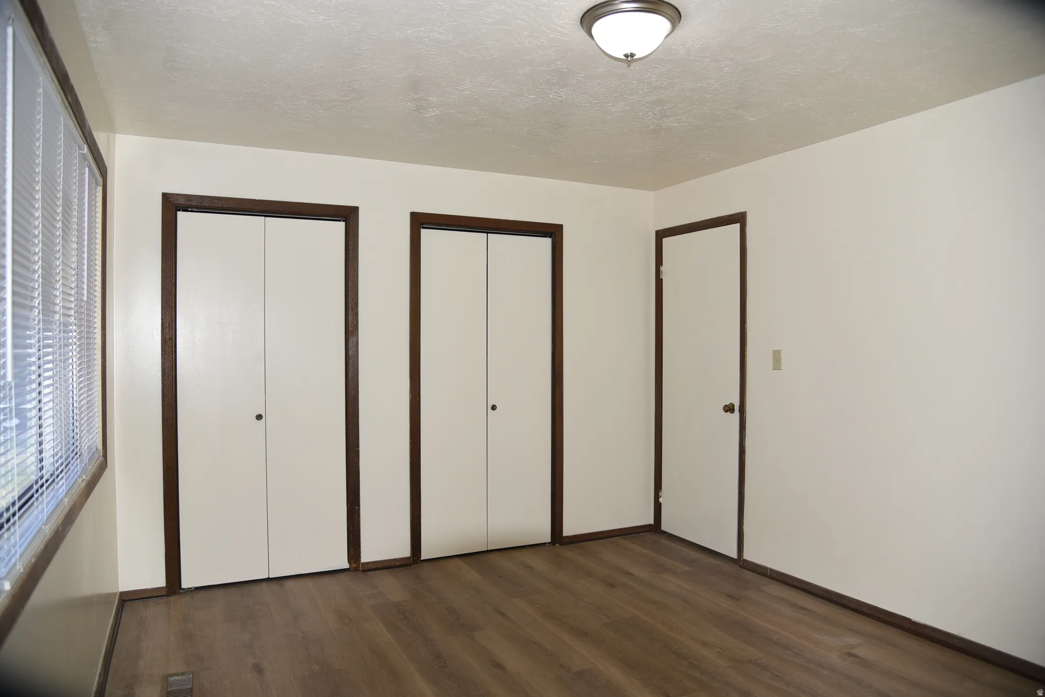 Interior room featuring wood-finish flooring, light-toned walls, and a semi-flush mount ceiling light