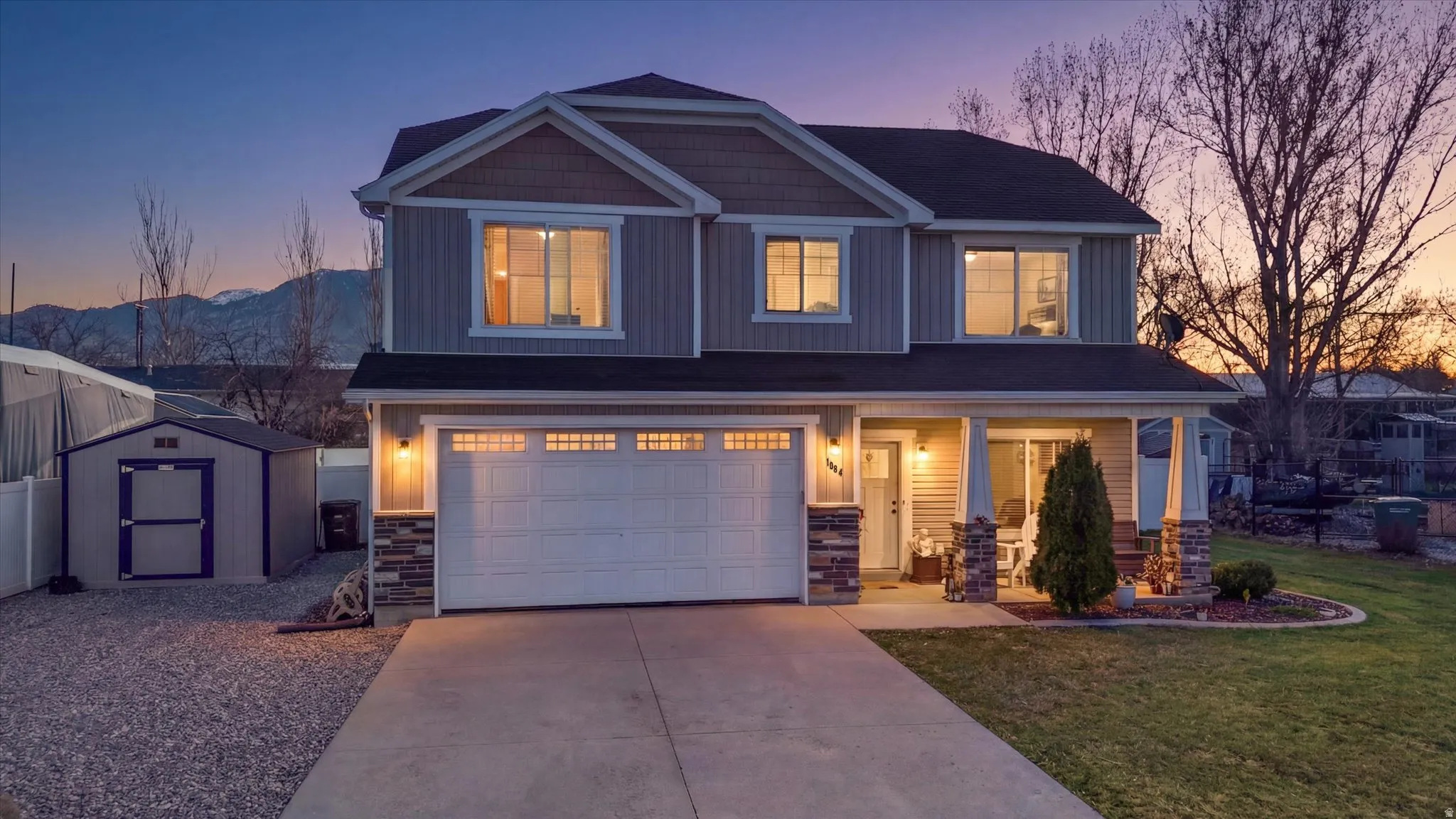 Craftsman-style home featuring stone siding, an attached garage, driveway, a porch, and a front lawn