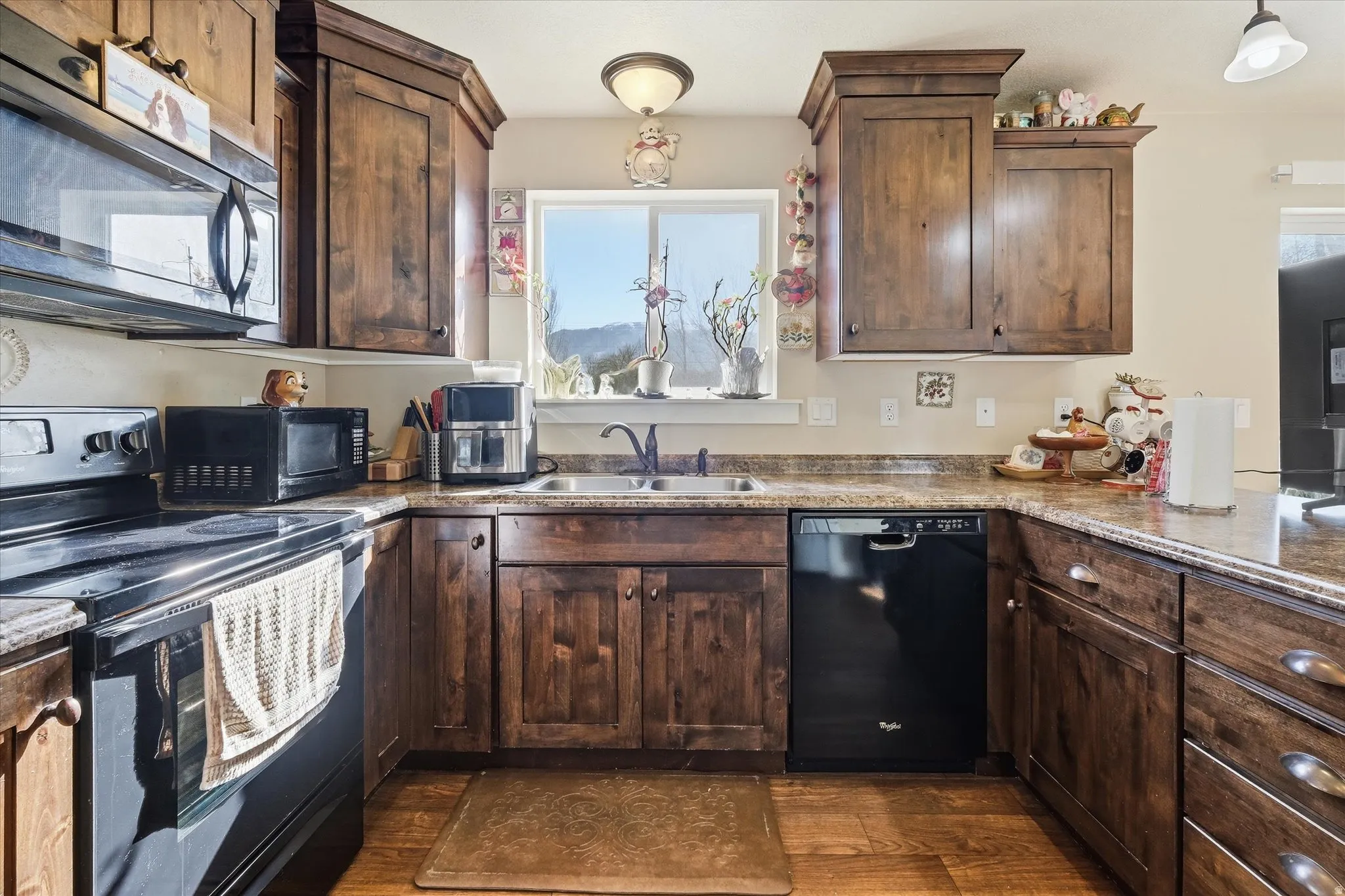 Kitchen with black appliances, dark wood finish cabinetry, and dark wood-style floors
