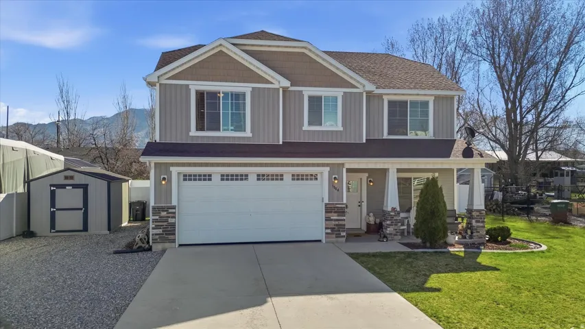 Craftsman-style home featuring stone siding, a porch, driveway, and a garage