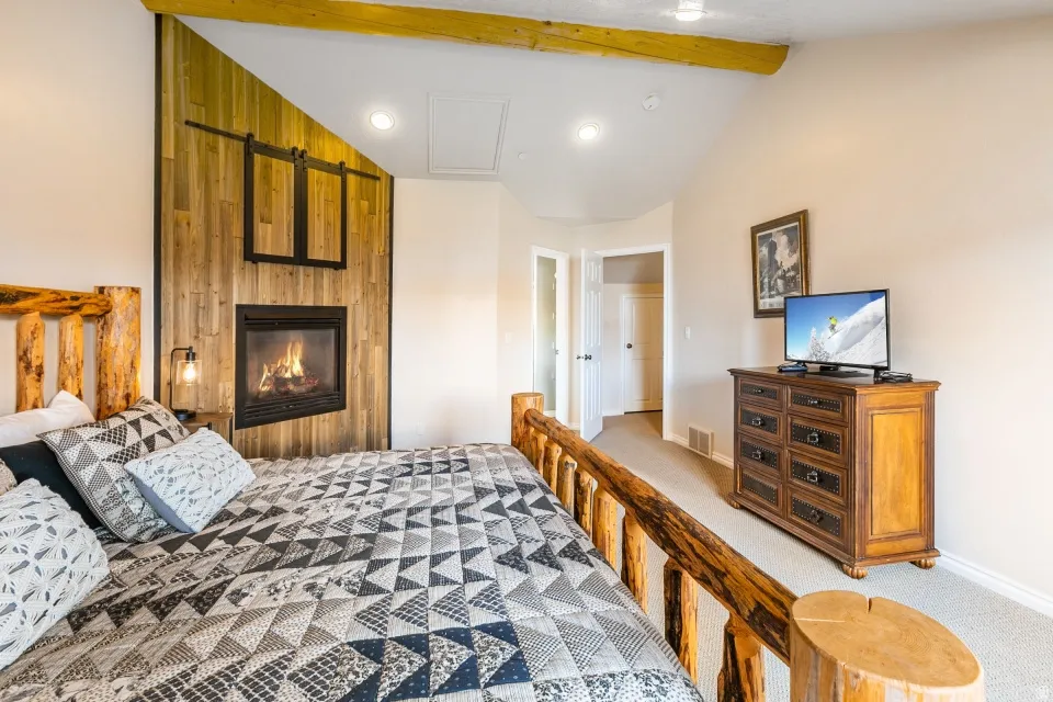 Bedroom featuring lofted ceiling with beams, light carpet, and a fireplace