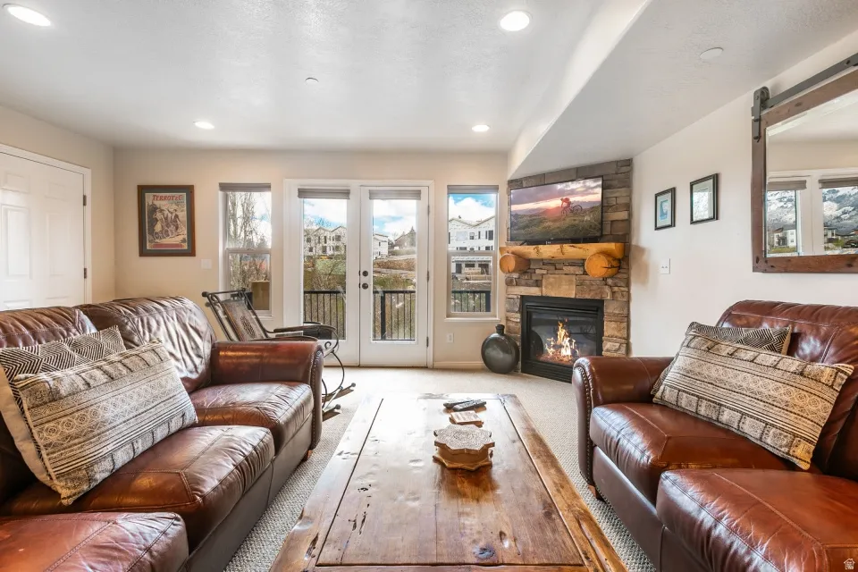 Carpeted living room featuring a stone fireplace, recessed lighting, and a barn door