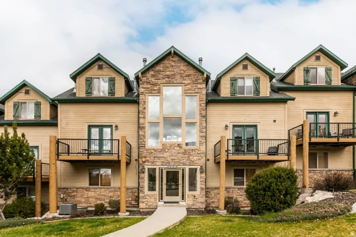 Rear view of property featuring french doors, stone siding, and a yard