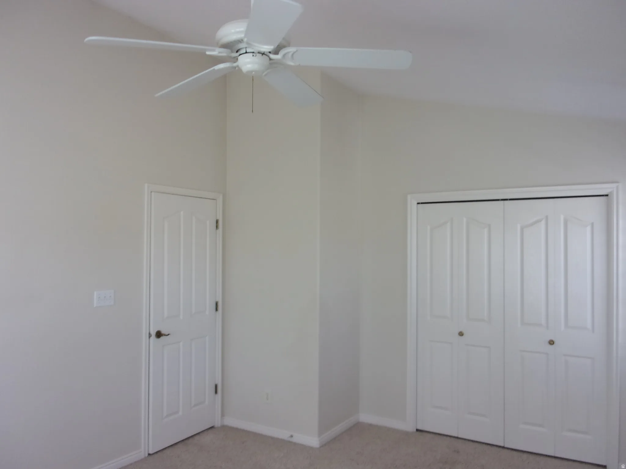Unfurnished bedroom featuring vaulted ceiling, light carpet, a ceiling fan, and a closet