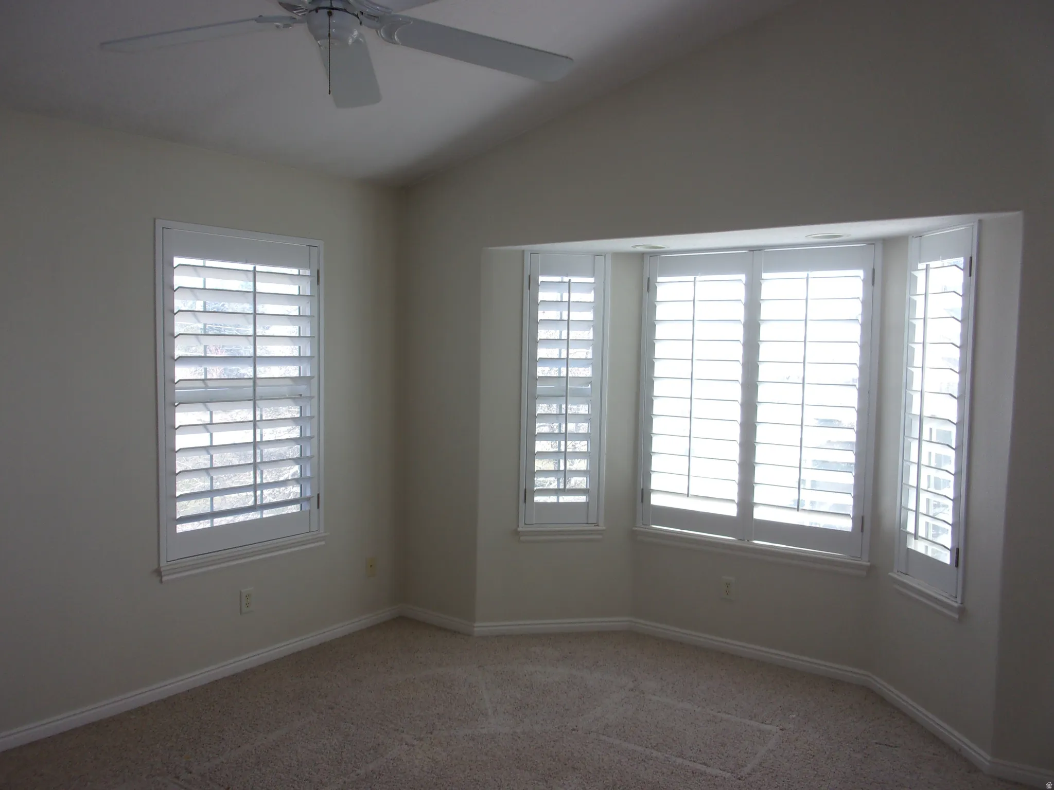 Carpeted empty room featuring a ceiling fan and lofted ceiling