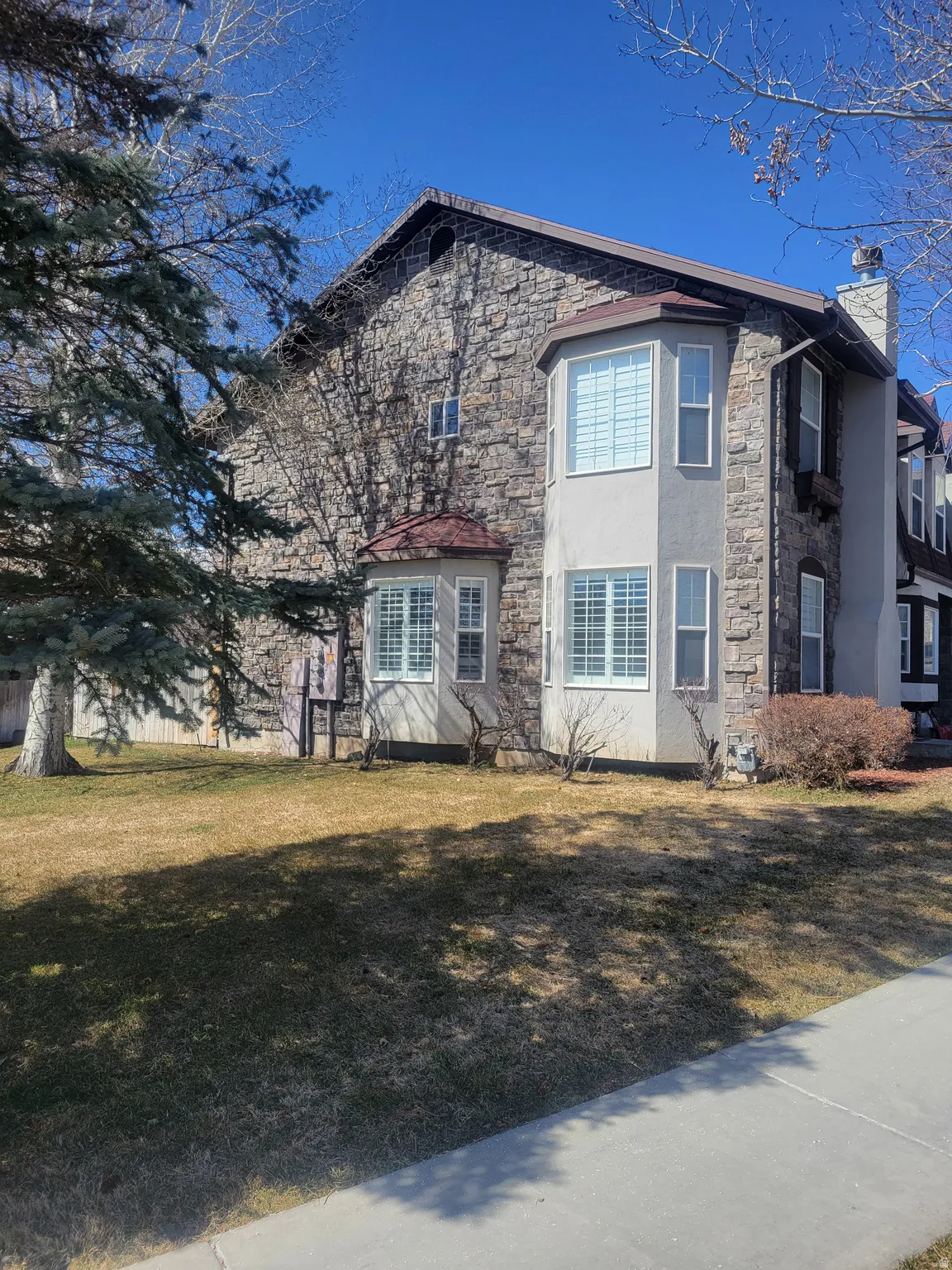 View of front of house featuring stone siding, a chimney, stucco siding, and a front yard