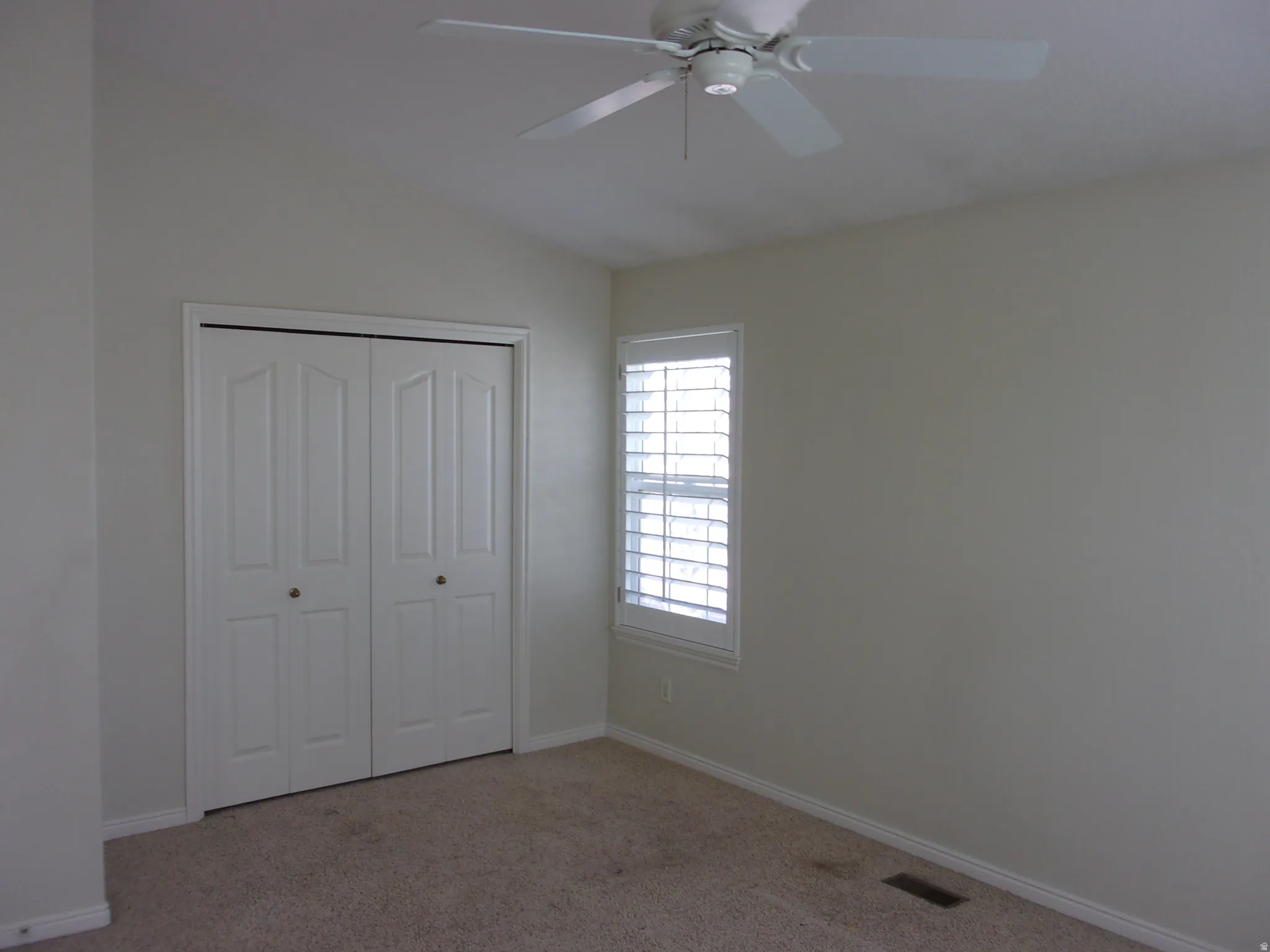 Unfurnished bedroom featuring light carpet, a closet, ceiling fan, and lofted ceiling