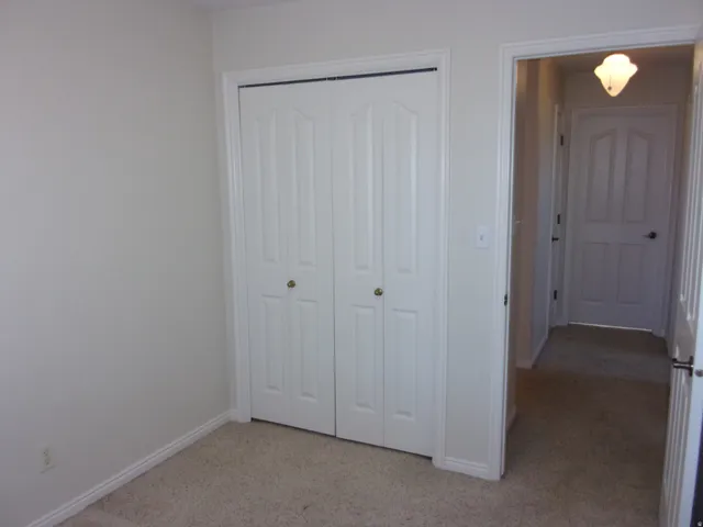 Unfurnished bedroom with light carpet and a closet