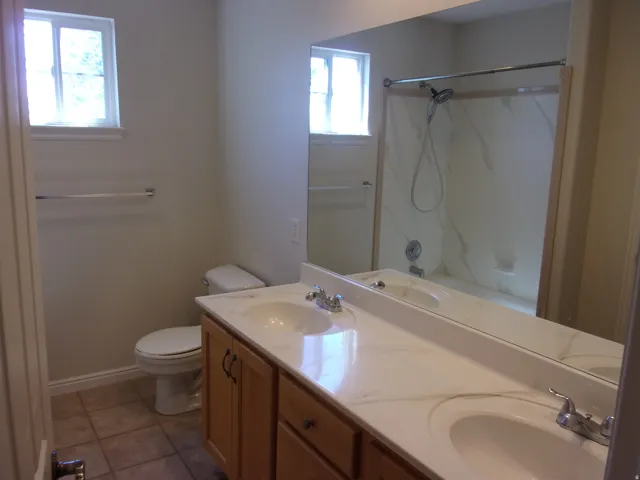 Bathroom featuring double vanity, light tile patterned flooring, and a shower