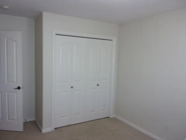 Unfurnished bedroom with a closet and light carpet