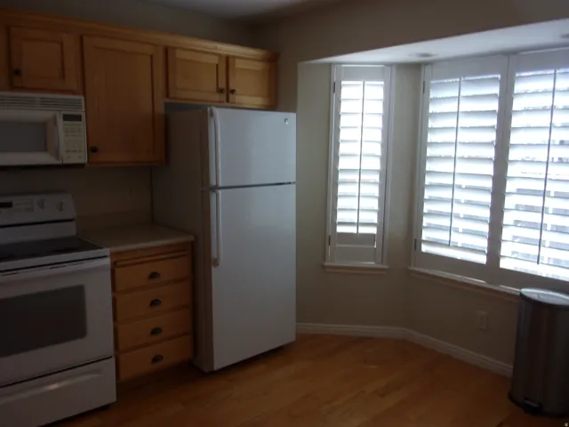 Kitchen featuring white appliances, light wood-style floors, light countertops, and light wood finish cabinetry