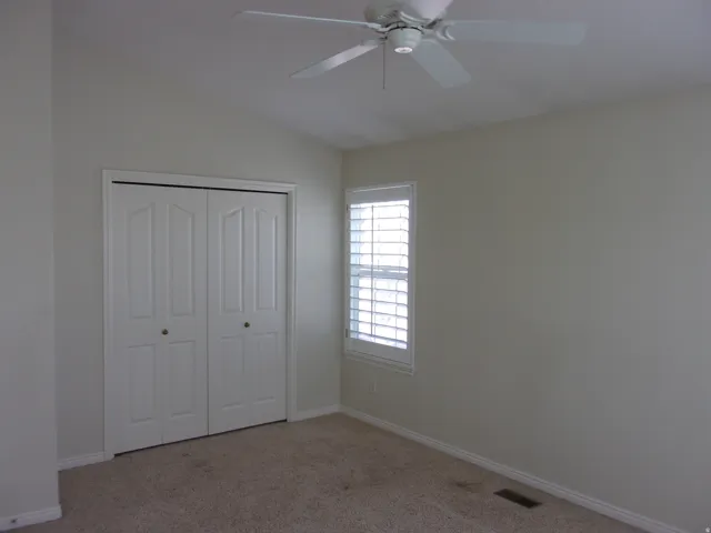 Unfurnished bedroom featuring light carpet, a closet, ceiling fan, and lofted ceiling