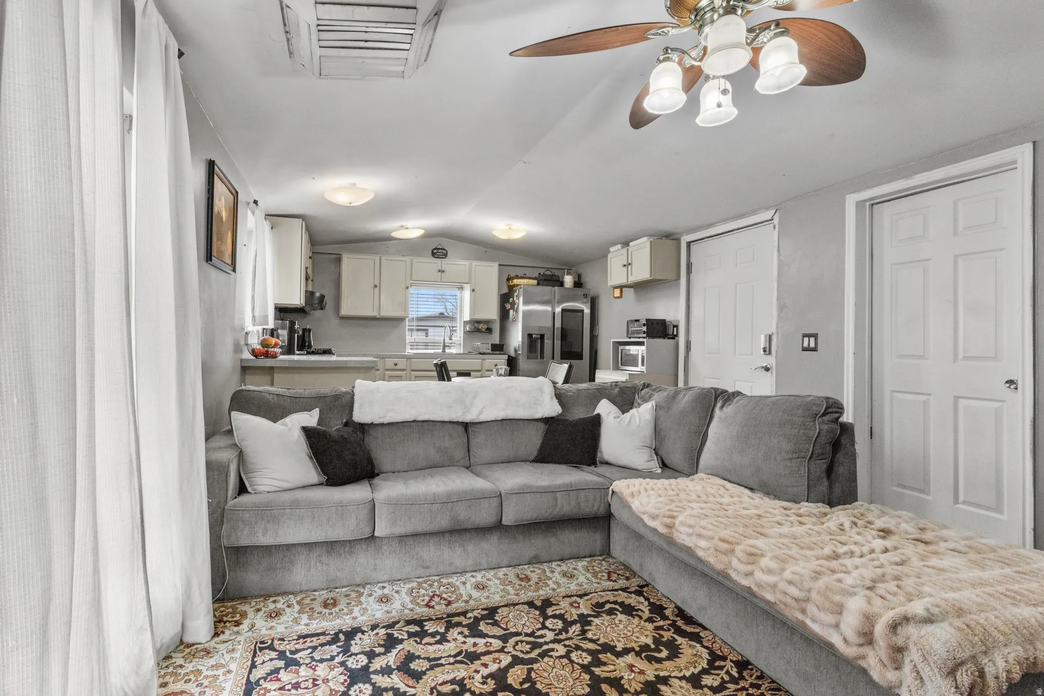 Living area with vaulted ceiling, cooling unit, and a ceiling fan