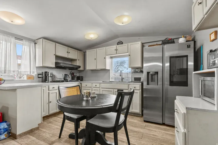 Kitchen with stainless steel fridge, light countertops, and light wood-style flooring