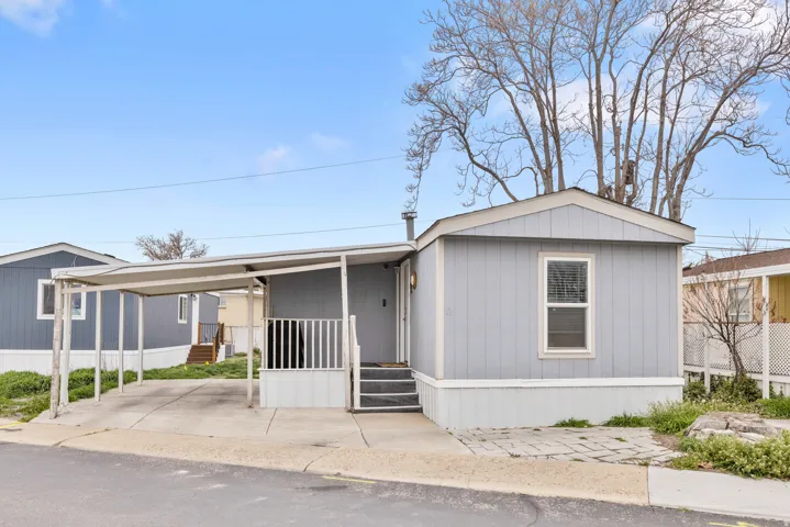 Manufactured / mobile home with a porch, a carport, and concrete driveway