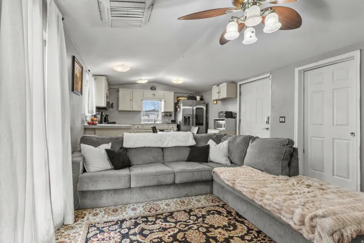 Living area with vaulted ceiling, cooling unit, and a ceiling fan