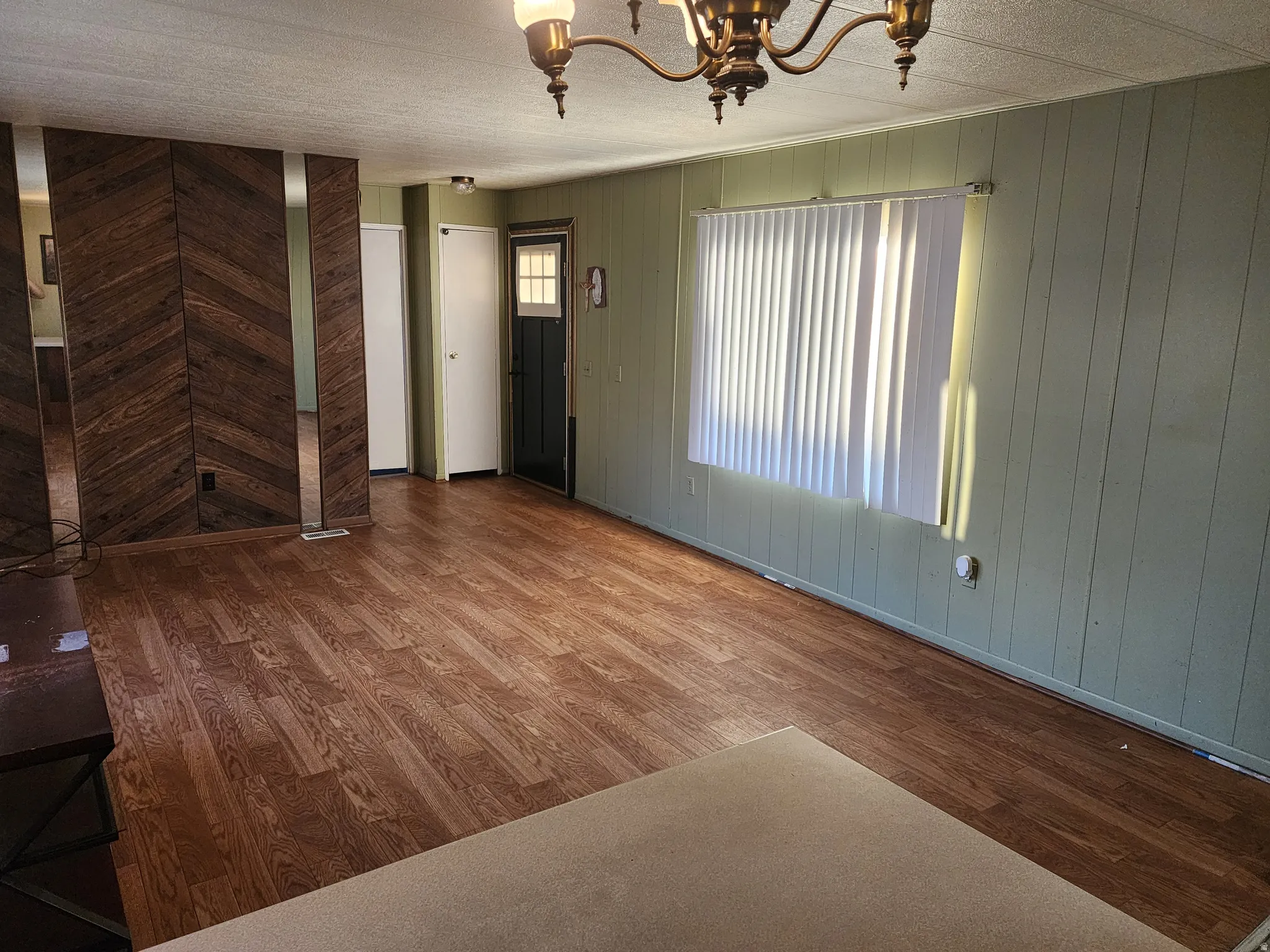 Unfurnished dining area featuring dark wood-type flooring, wood walls, and suspended lighting