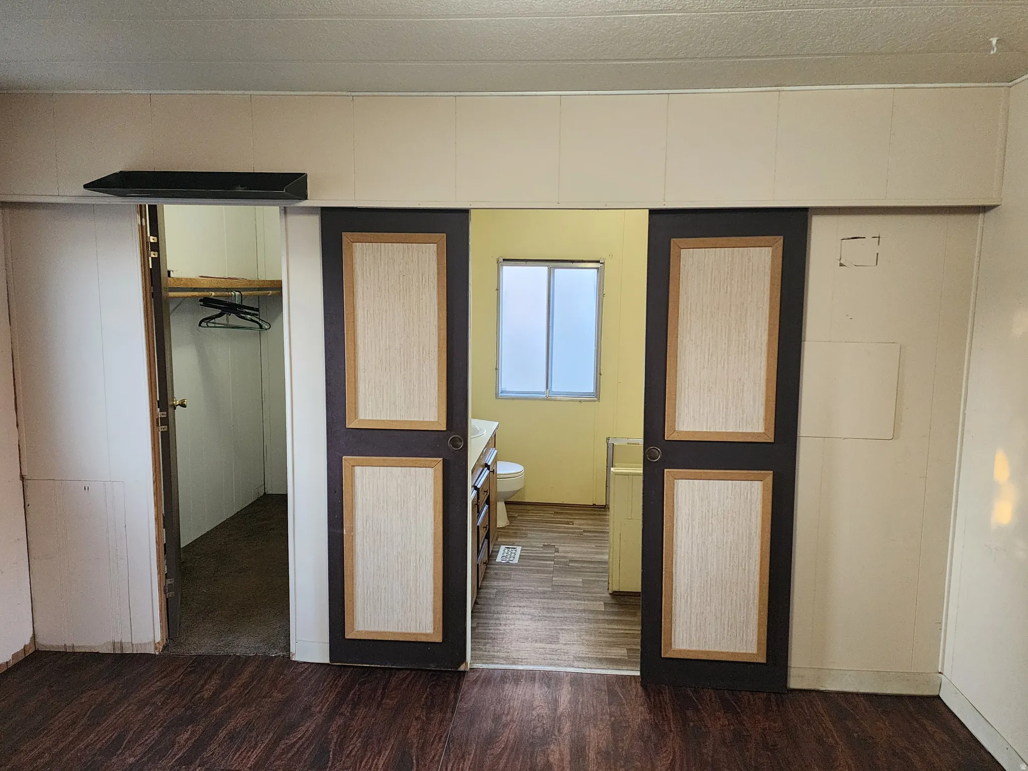 Unfurnished bedroom with dark wood-style floors and a spacious closet