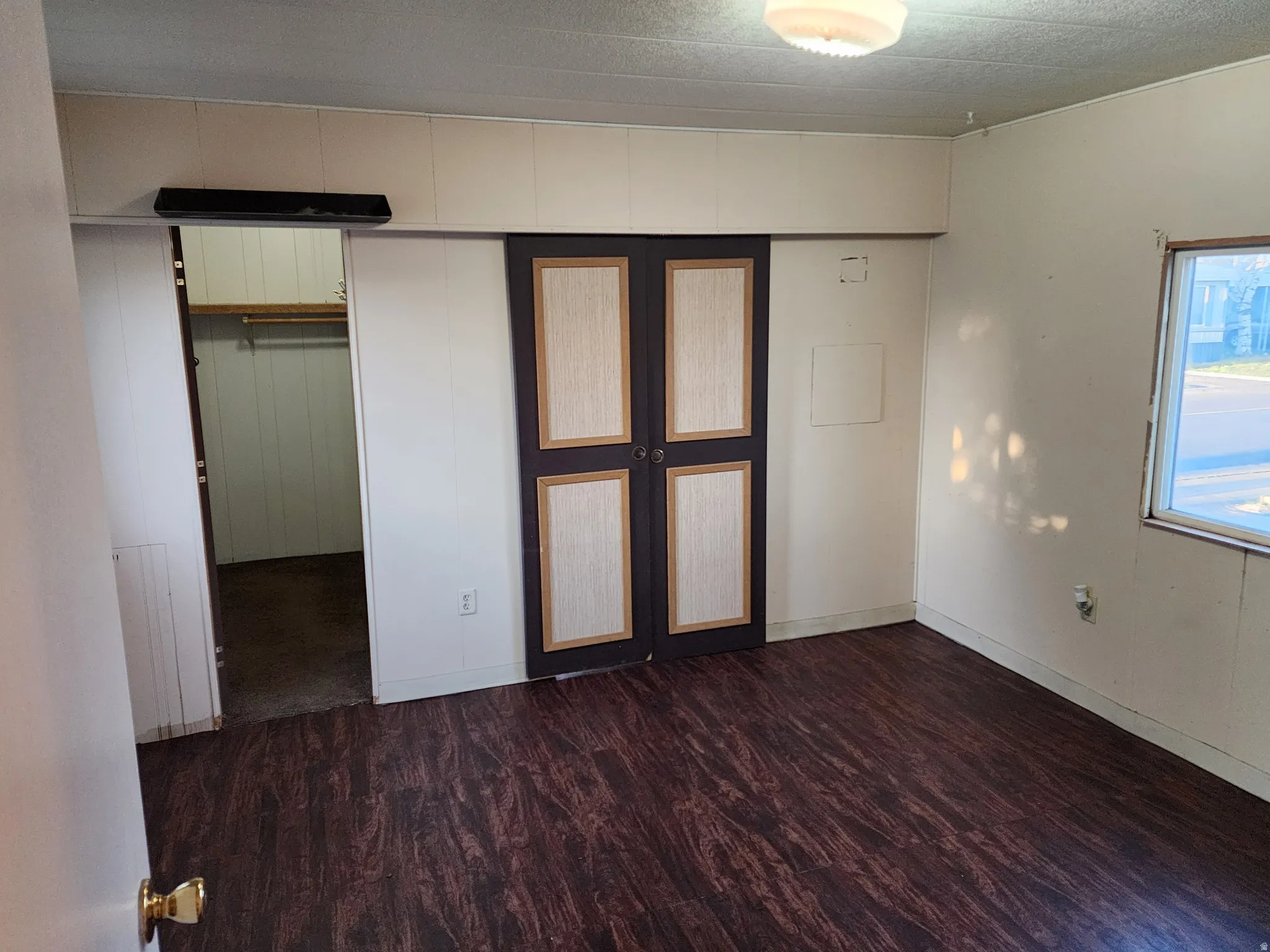 Unfurnished bedroom featuring dark wood-style flooring, a walk in closet, and french doors