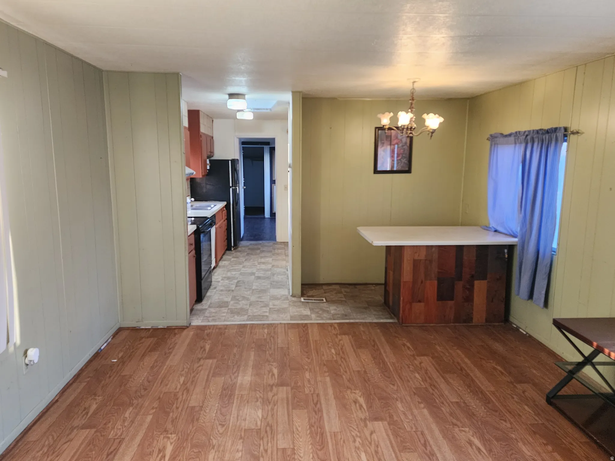 Kitchen featuring light countertops, a chandelier, light wood-type flooring, a peninsula, and wood walls