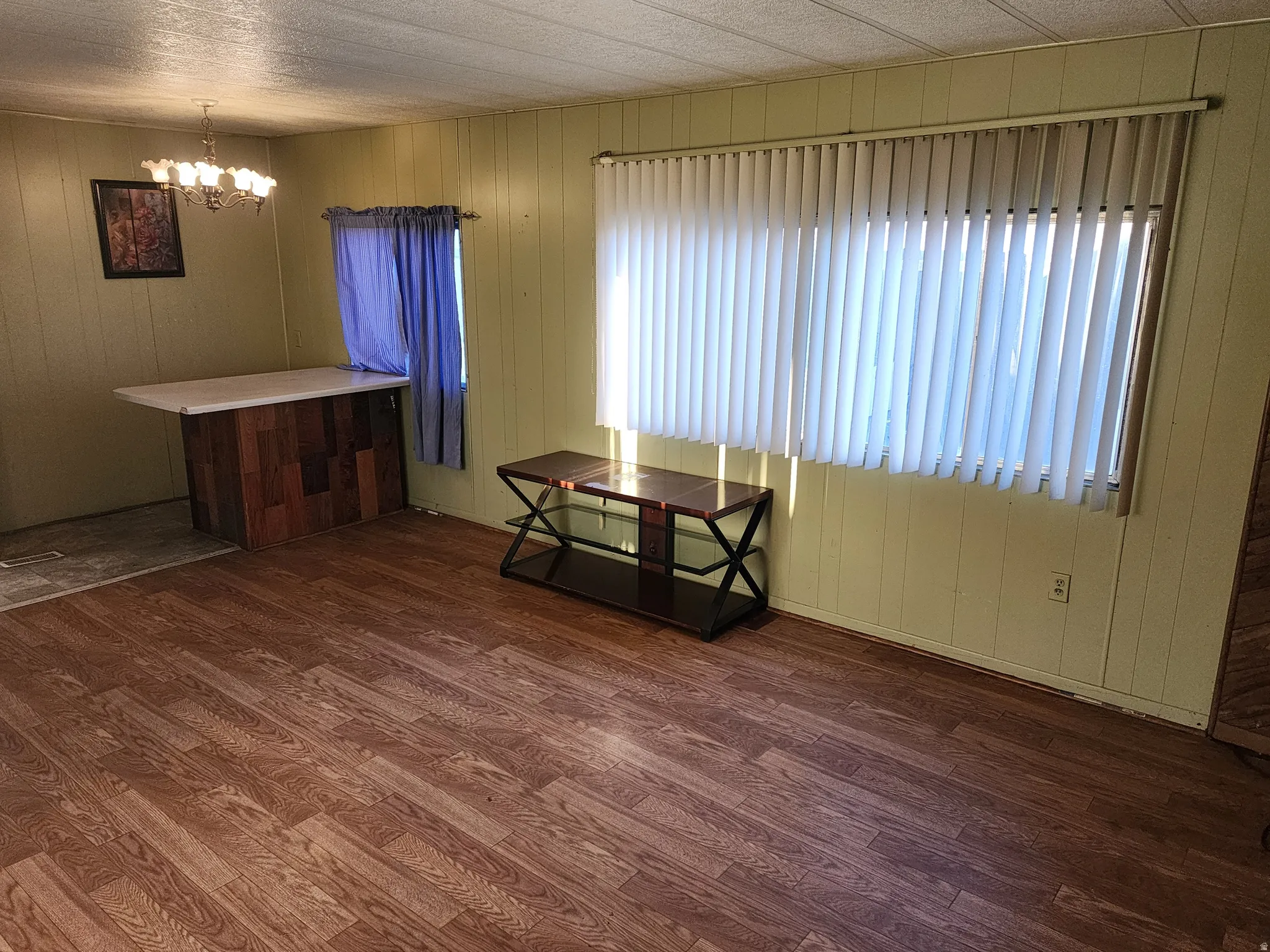 Dining room with dark wood-type flooring, hanging lights, and wood walls