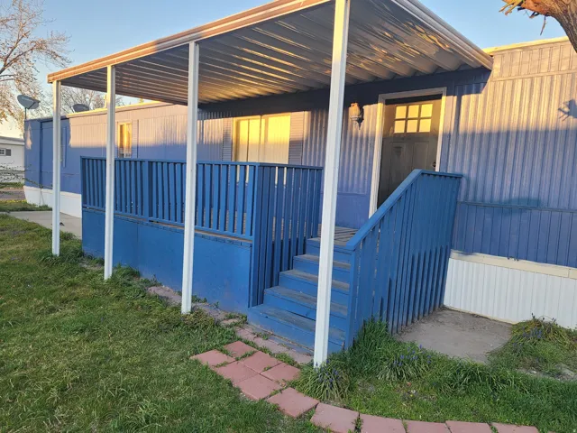 Doorway to property with a lawn and covered porch