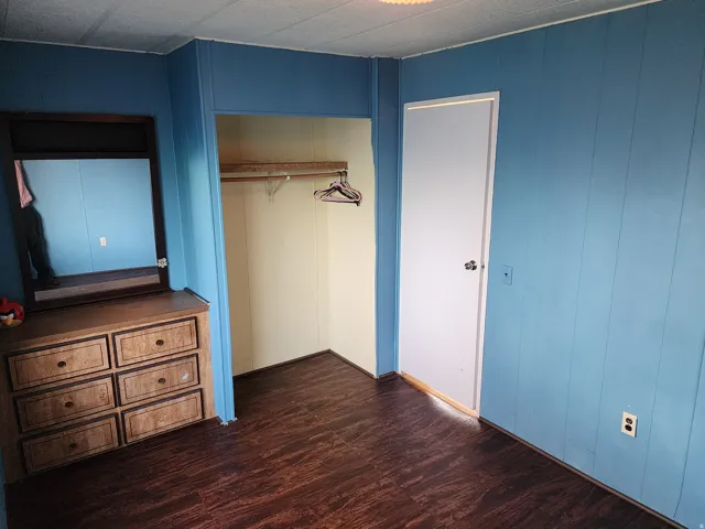 Unfurnished bedroom with dark wood-style flooring and a closet
