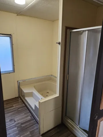 Full bathroom with a garden tub, a stall shower, and dark wood-type flooring