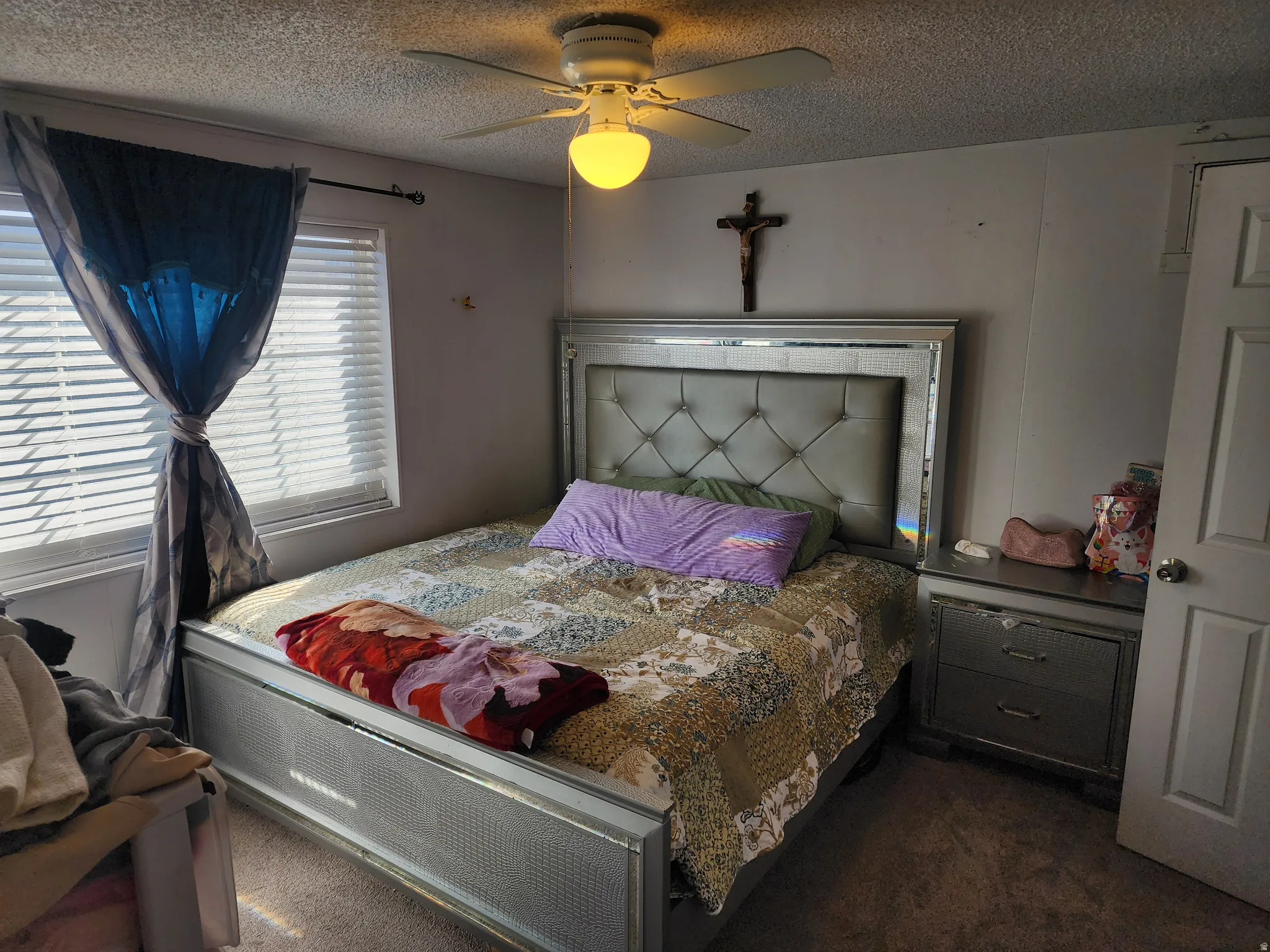 Bedroom with a textured ceiling, dark colored carpet, and ceiling fan