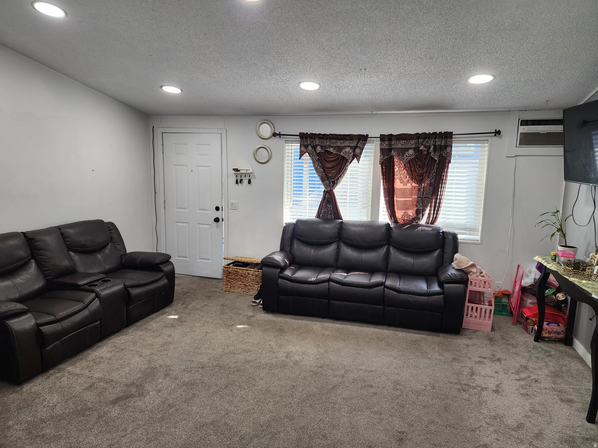 Carpeted living room with a textured ceiling and recessed lighting
