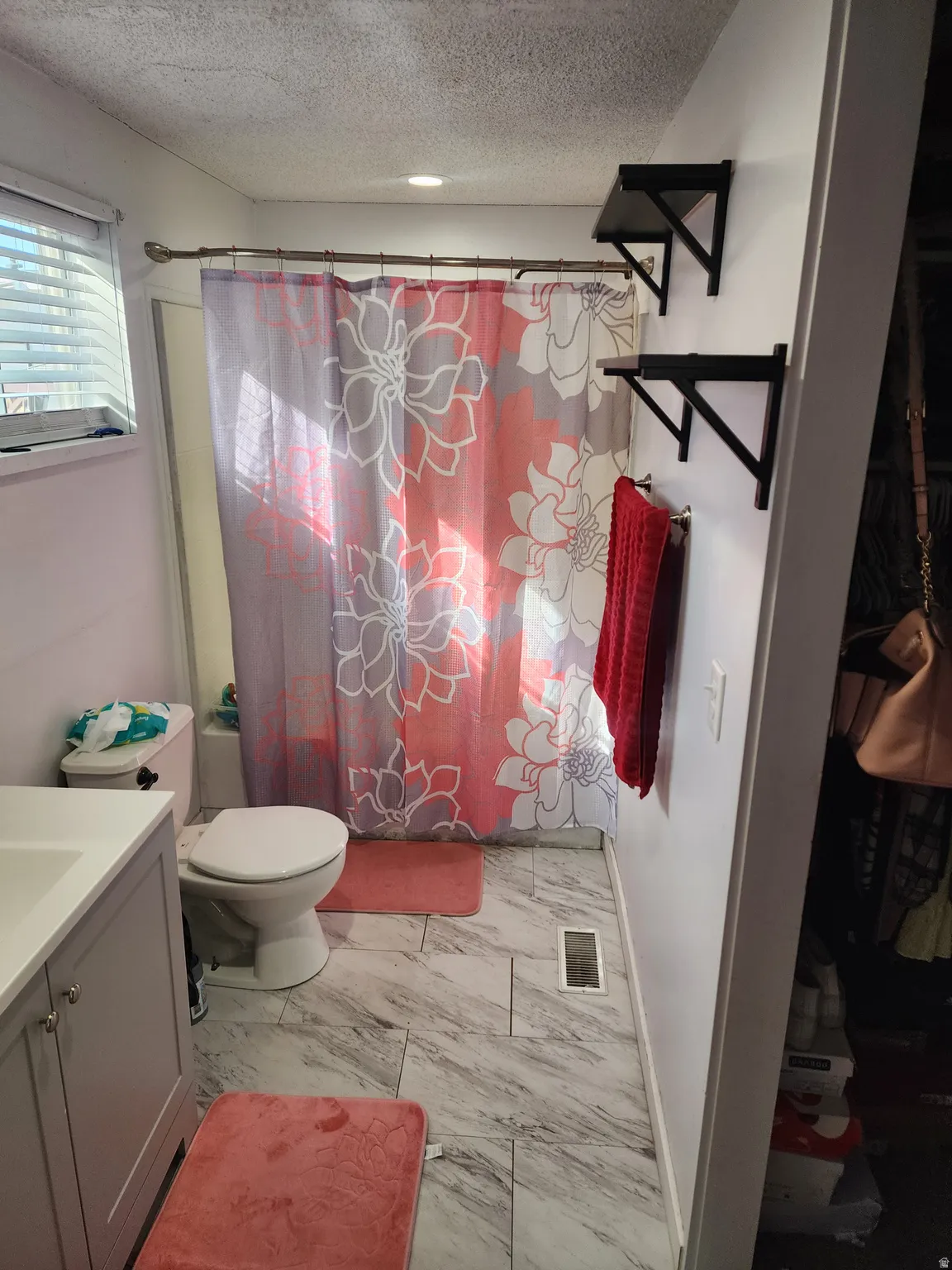 Bathroom featuring vanity, a textured ceiling, and light marble finish floors