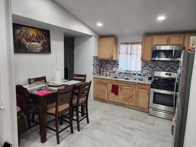 Kitchen featuring stainless steel appliances, decorative backsplash, recessed lighting, and light stone counters