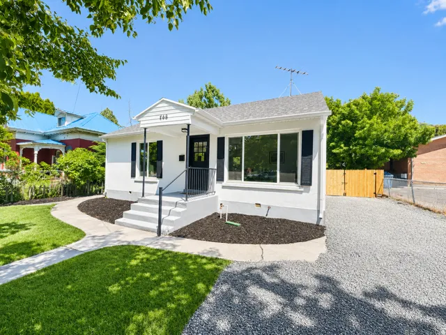 White exterior featuring black window shutters, a front porch with black railing, and a gray shingle roof