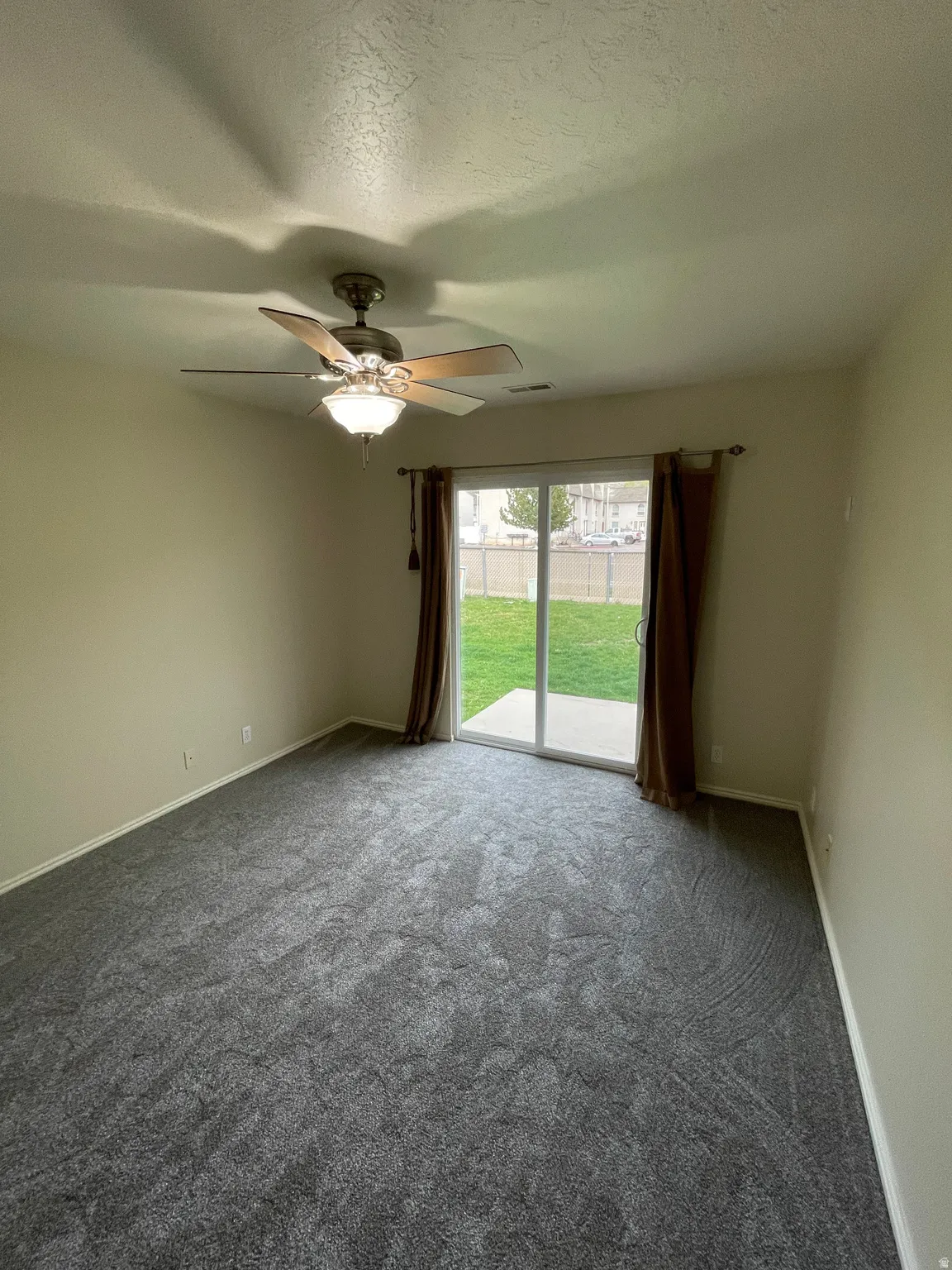 Carpeted empty room featuring a textured ceiling and ceiling fan