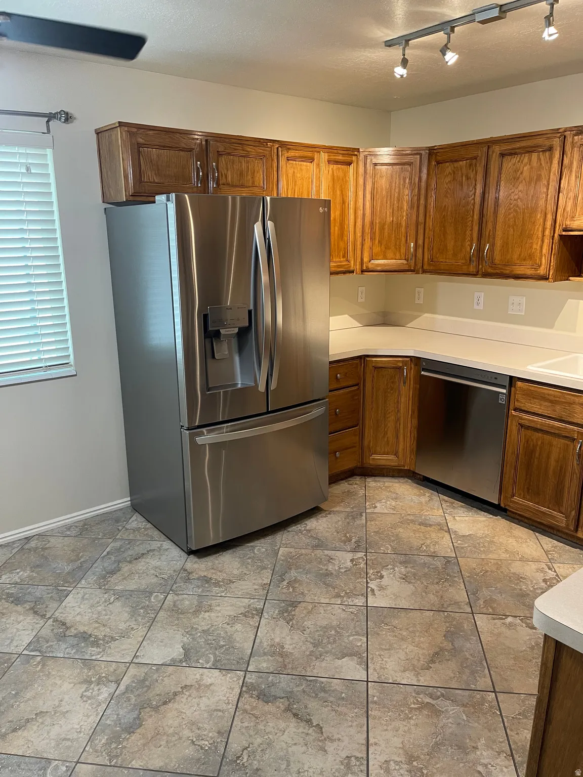Kitchen with light countertops, stainless steel appliances, wood finish cabinets, and rail lighting
