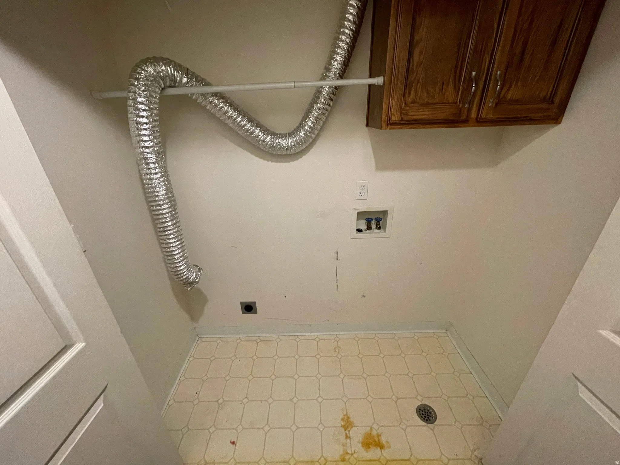 Laundry area featuring light floors, electric dryer hookup, and cabinet space