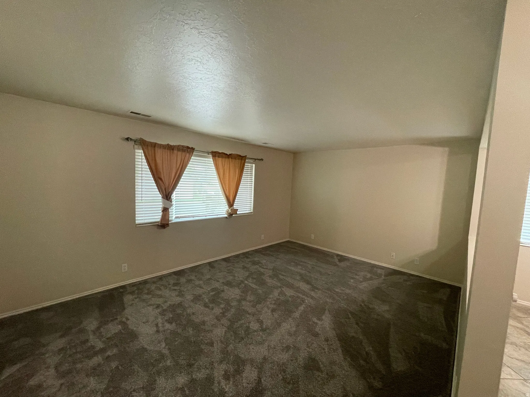 Unfurnished room featuring dark colored carpet and baseboards
