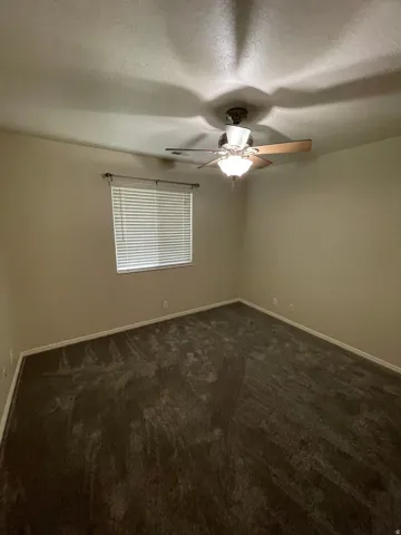 Spare room with dark carpet, ceiling fan, and a textured ceiling